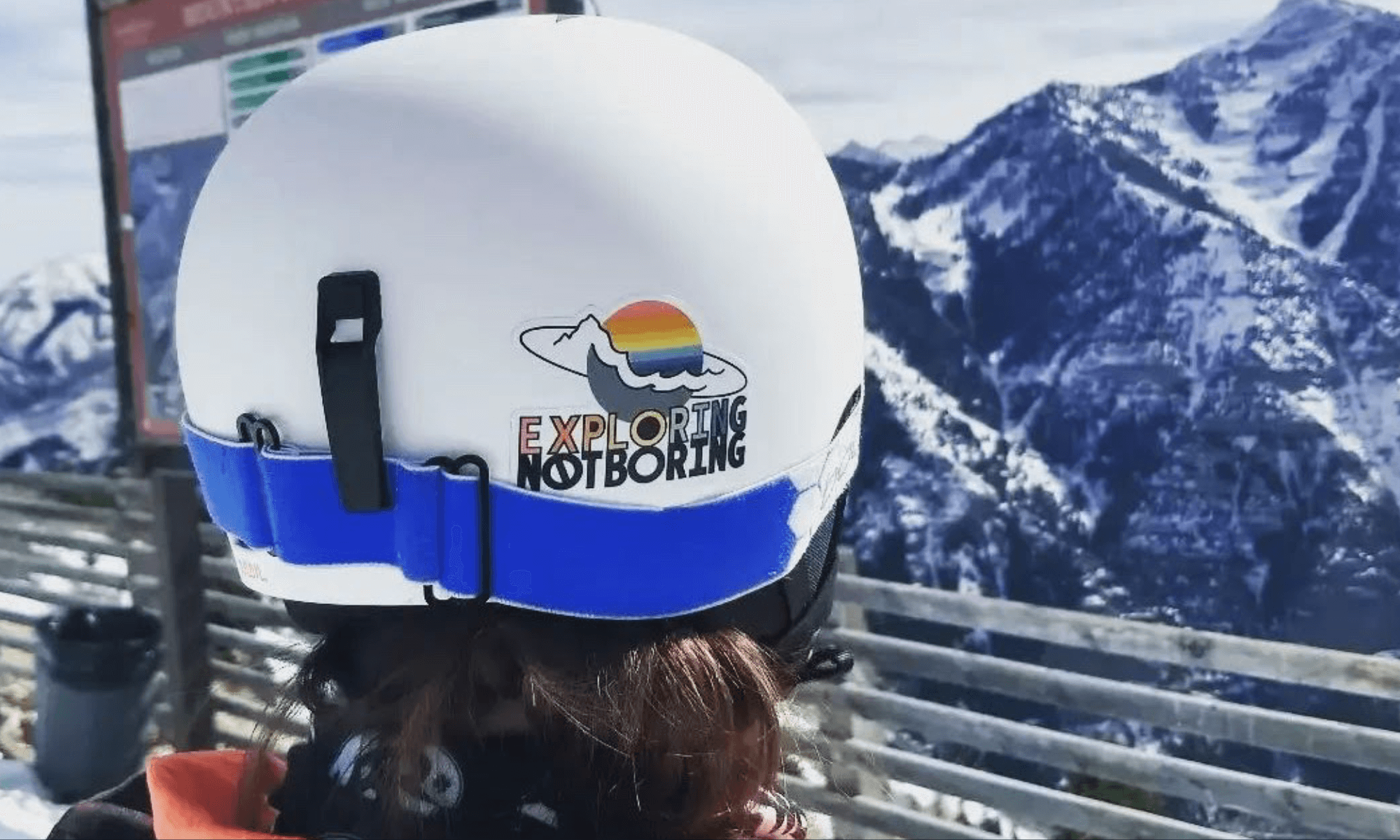 Photo of a snowboarder rockin' our EXPLORINGNOTBORING sticker on top of the Utah Mountains