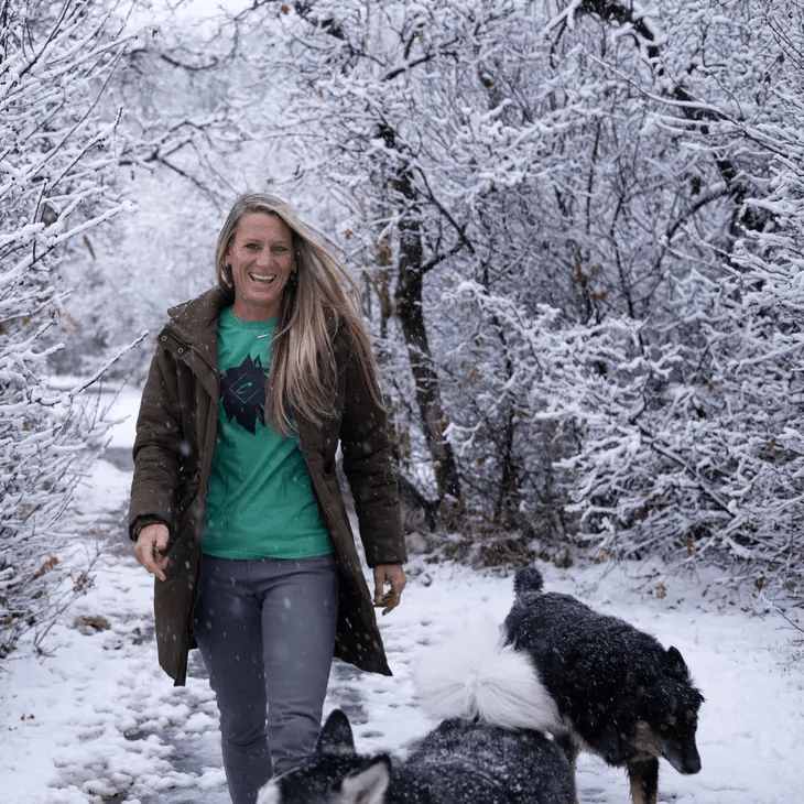 Tauni Huddleston, a tall, long-haired blonde caucasian female walking in a winter wonderland with her beloved huskies  - Casanova Guided Tours