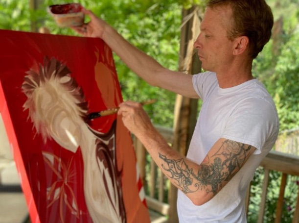 André Hoggan Painting on a back patio with a gorgeous green back drop.